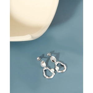 Detail of irregular silver hoop earrings with white pearl pendants on blue background
