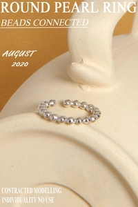 Detailed close-up of a minimalist silver beaded open ring on a beige ceramic surface