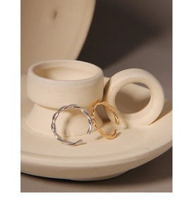 Detailed view of silver and gold twisted rope stackable rings on ceramic pottery