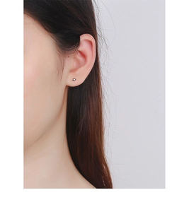Close-up of minimalist S925 sterling silver ball stud earrings on model earlobe