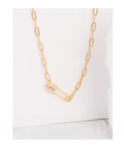 Detailed close-up of gold safety pin necklace featuring sparkling crystal accents