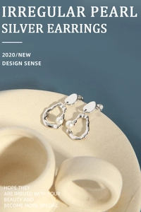 Macro shot of irregular S925 silver hoop earrings with white pearls on a ceramic plate