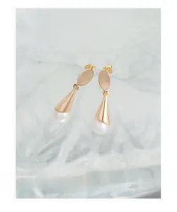 Detailed close-up of S925 sterling silver stamp and lustrous freshwater pearl on gold earring