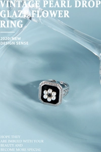Macro shot of vintage pearl flower ring with black enamel inlay and adjustable silver band