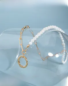 Detail of a pearl and gold rectangle chain necklace with a hammered ring pendant