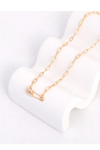 Close-up of gold paperclip chain necklace with a crystal-studded safety pin pendant