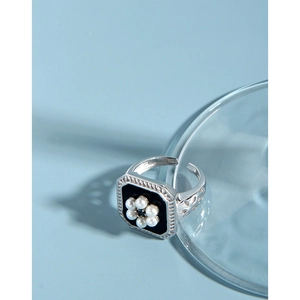 Detailed macro view of S925 silver ring featuring black enamel and pearl flower patterns