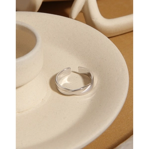 Close-up of a s925 silver twisted ring on a ceramic plate with soft side lighting