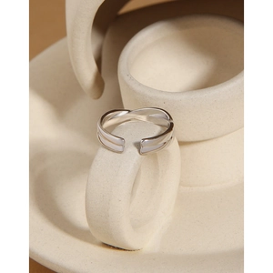 Macro shot of silver twisted open ring with white enamel inlay on a ceramic base