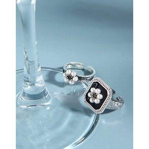 Detailed macro shot of vintage floral silver ring with pearl detail and black enamel