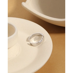 Detail of silver twisted rope ring placed on a ceramic plate edge with soft lighting