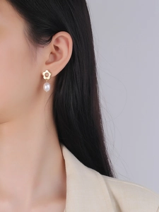 Detail shot of elegant gold flower stud earrings with natural baroque pearls on model