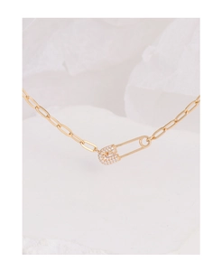 Macro shot of gold paperclip chain necklace with sparkling zircon safety pin pendant