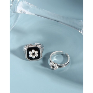 Vintage S925 silver flower ring set with black glaze and pearls on light blue background