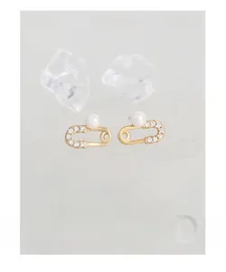 Macro shot of gold safety pin earrings with sparkling zircon stones and white faux pearls
