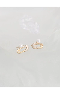 Detailed view of gold safety pin earrings with sparkling pavé diamonds and a white pearl