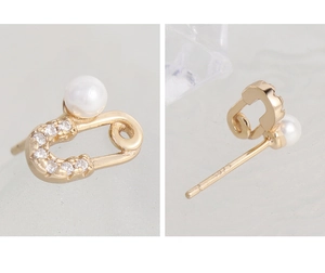 Macro detail of gold safety pin earrings with S925 hallmark, pearls and sparkling zircons