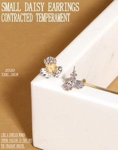 Close-up of S925 silver daisy stud earrings with gold center on marble stand