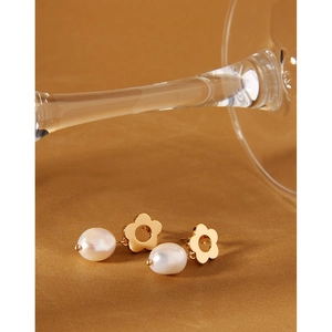 Detail of gold floral stud earrings with white pearls on elegant gold surface