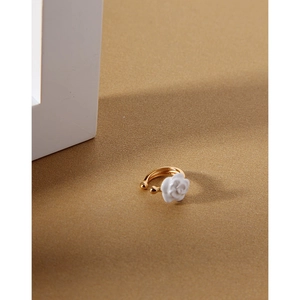 Detail shot of a golden ear cuff featuring a delicate 3D white camellia flower
