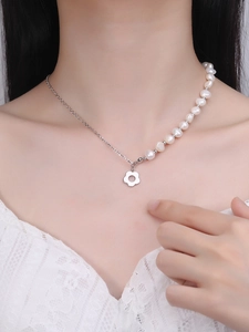 Detail of asymmetric necklace featuring fresh pearls and silver flower charm on neck