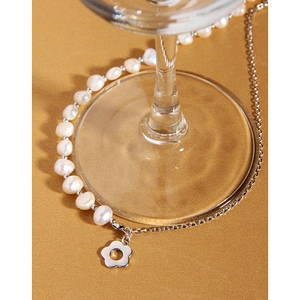 Macro detail of asymmetric S925 silver necklace with irregular pearls and flower charm