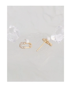 Detailed close-up of golden safety pin earrings with sparkling crystals and white pearls