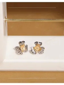 Macro shot of silver textured petal earrings with golden stamen on marble surface