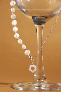Detail of asymmetrical S925 silver necklace with pearls and flower pendant on glass