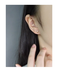Detail of gold heart safety pin earrings with small pearl and sparkling micro diamonds