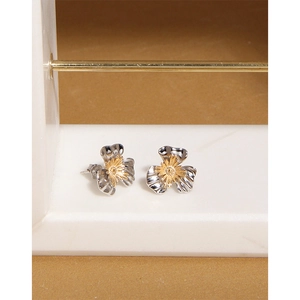 Macro detail of S925 sterling silver flower earrings with golden stamen on marble stand