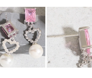 Macro view of S925 silver stud earrings with pink zircon and white pearl heart charms