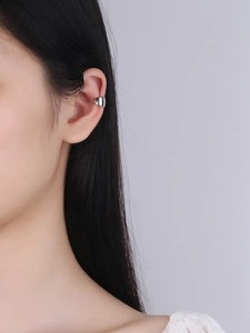 Macro detail of a polished S925 sterling silver ear cuff shown on a model's ear
