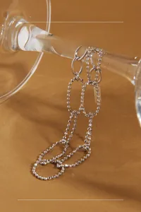 Detailed view of S925 sterling silver chain bracelet draped on a wine glass stem