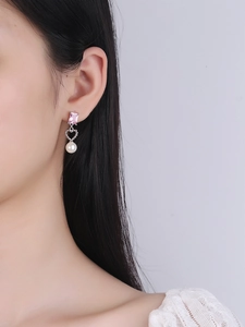 Detail of pink zircon and heart pearl earrings worn by a model in a close-up profile shot