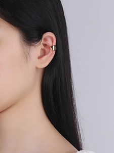Close-up of a minimalist gold ear cuff worn on the ear cartilage with a polished finish