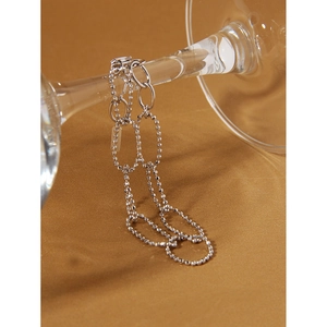 Detail of silver S925 sterling silver chain with beads draped on glass stem