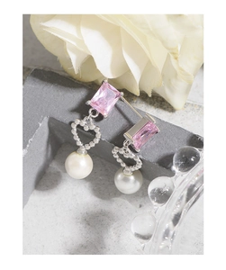 Detail of pink crystal heart earrings with white pearls on a stone display stand