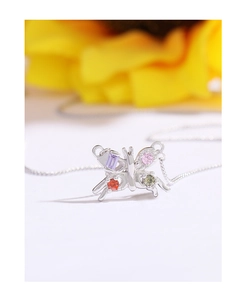 Macro shot of silver butterfly pendant with four colorful gemstones on floral background