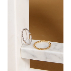 Dettaglio della trama ritorta irregolare su anelli aperti in oro e argento minimalisti