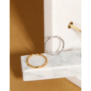 Dettaglio di anelli a fune intrecciata oro e argento su marmo con sfondo marrone elegante