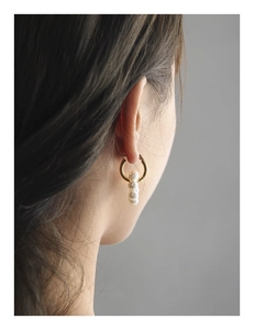 Détail de boucles d'oreilles créoles dorées en argent S925 avec perles sur un mannequin
