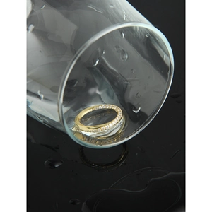 Bague Mobius dorée avec pavé de zircons dans une mise en scène créative en verre
