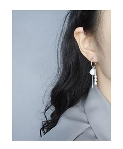 Detail of S925 silver tassel earring with baroque pearl and fine metal chain on model