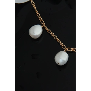 Macro shot of minimalist gold chain with two white baroque pearls on black surface