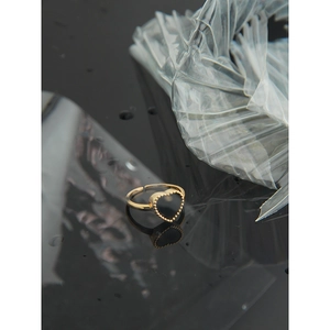 Detailed view of an adjustable gold heart ring with black onyx and bead edge detailing