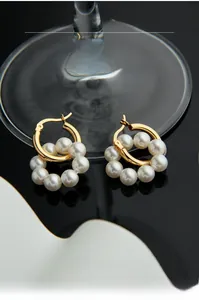 Détail de boucles d'oreilles créoles dorées en argent S925 avec perles blanches en grappe