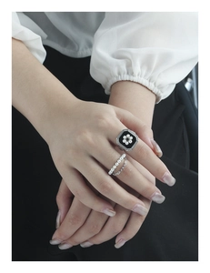 Detail of silver rings featuring black enamel floral pearl and delicate chain layered design