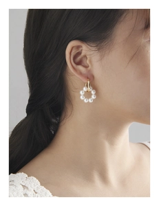 Gros plan d'un mannequin portant des créoles dorées avec un pendentif couronne de perles