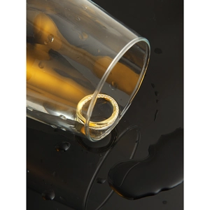 Gros plan d'une bague Mobius dorée avec zircons sur un fond miroir créatif avec eau